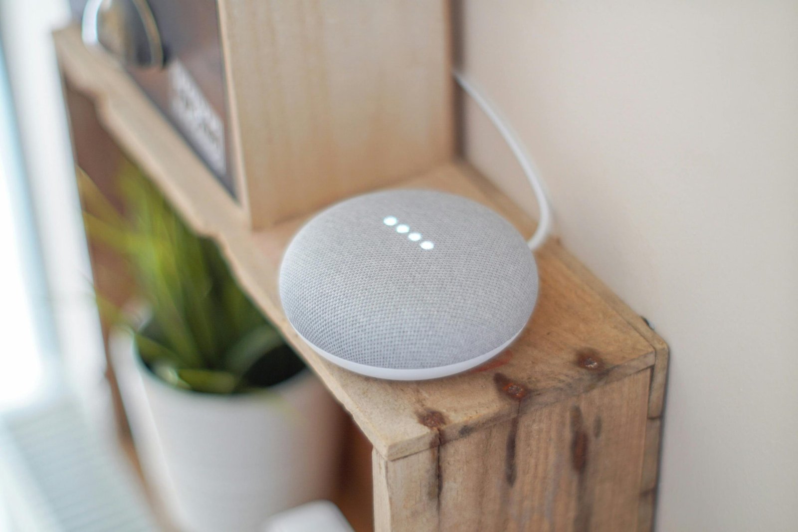 A Google Home Mini smart speaker on a wooden shelf, blending technology with home decor.